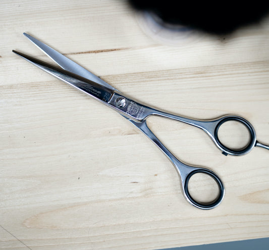 Affordable professional hair scissors from Kiepe sit on a barber's stationl