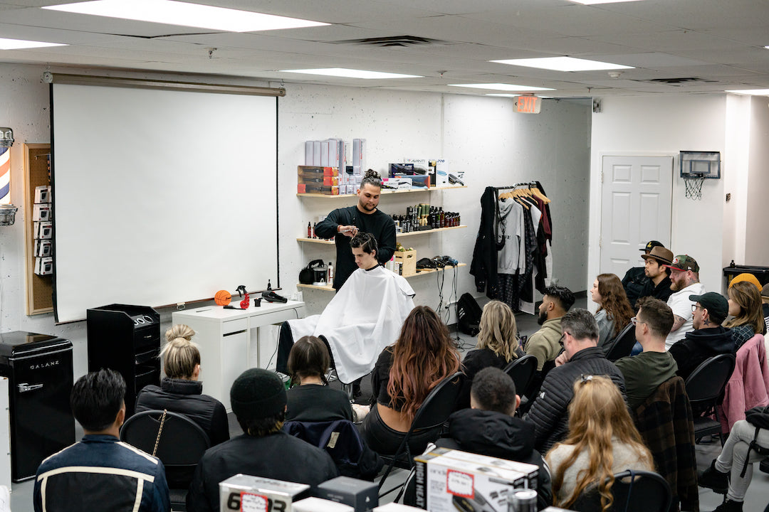 Professional barber and educator from Vancouver, Dro, demonstrating hair cutting techniques in front of a crowd.